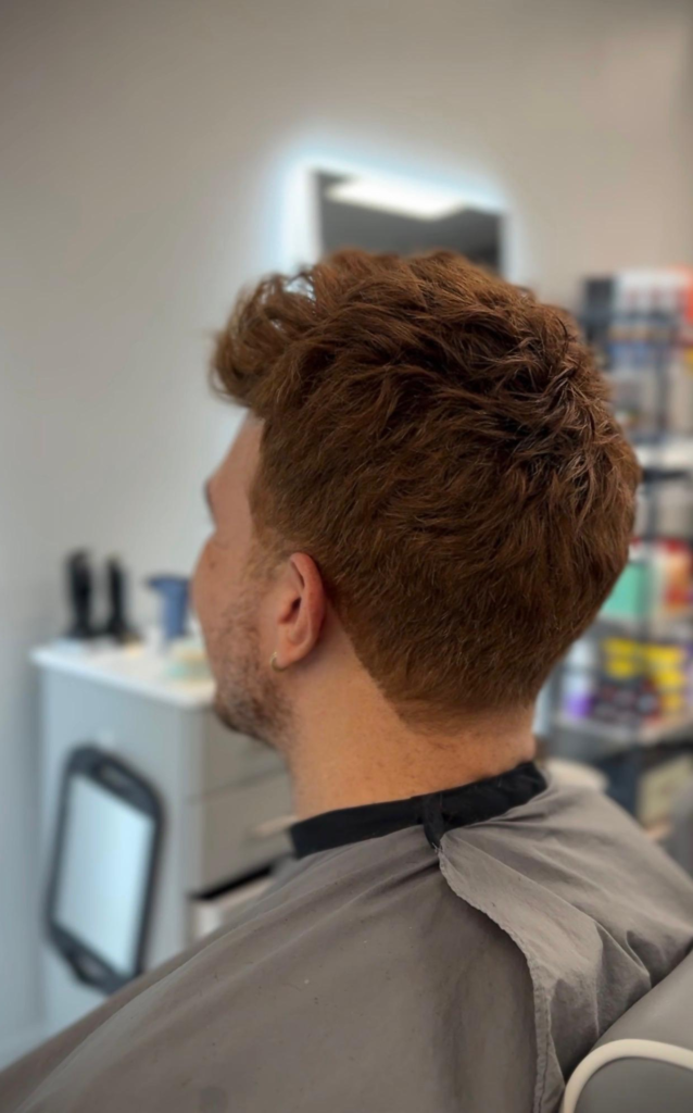 Men's hair system styled as a modern mullet in auburn, back view