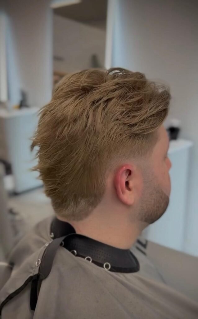 Men's hair system styled as a mullet in dark blonde, back side view